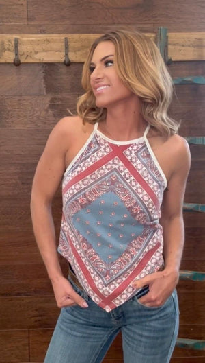 Woman wearing a patterned halter top and jeans against a wooden background