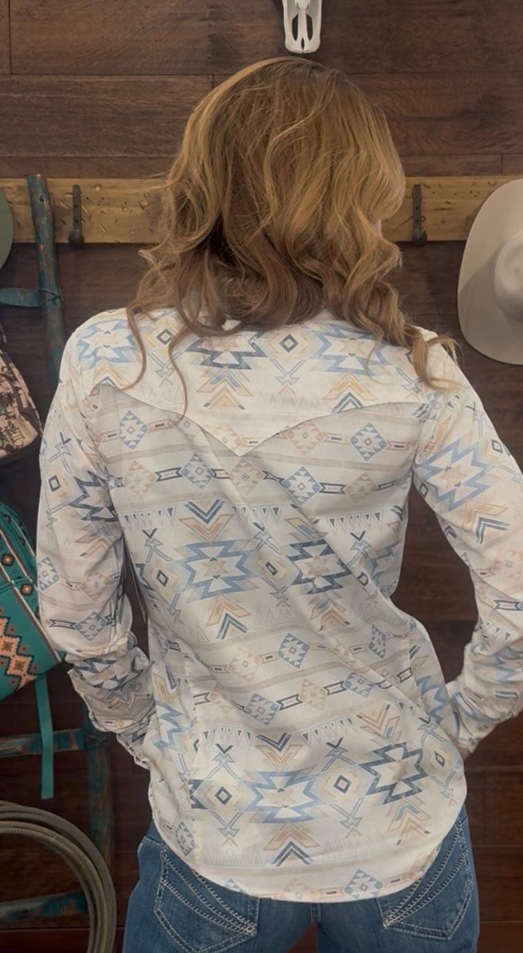 Person wearing a patterned long-sleeve shirt in a rustic setting