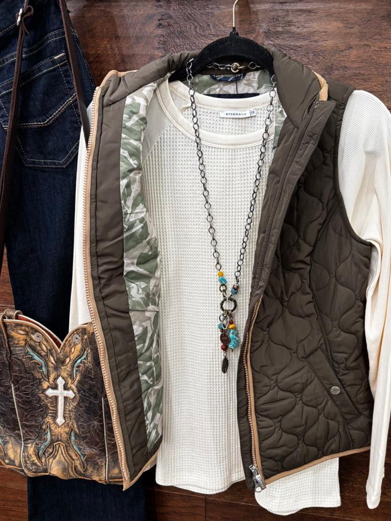 An earth tome quilted zip-up vest layered over a cream knit sweater