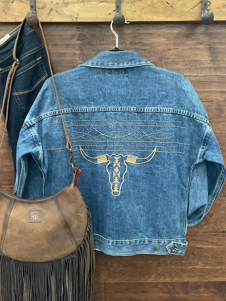 A blue denim jacket with a large embroidered steer skull design on the back. 