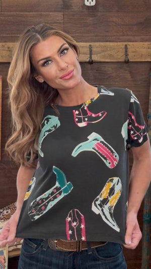 Woman wearing a black t-shirt with colorful snake designs in a casual setting.