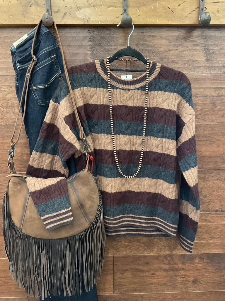 A striped cable-knit sweater in brown, beige, and charcoal. 