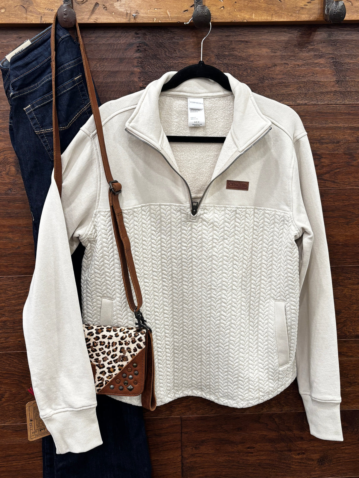 A cream-colored quarter-zip pullover sweater with a textured chevron pattern on the lower half