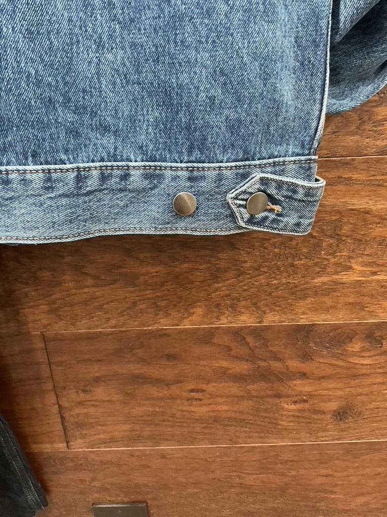 A blue denim jacket with a large embroidered steer skull design on the back. 