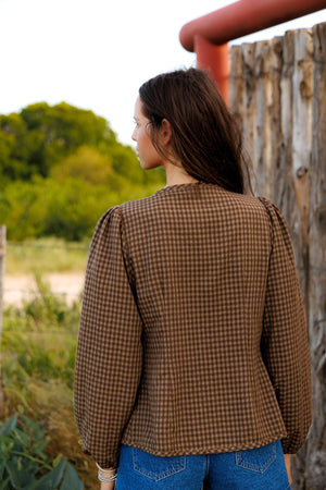 This charming blouse features a timeless brown checkered pattern and a stylish front tie detail, making it a versatile and fashionable addition to any wardrobe.