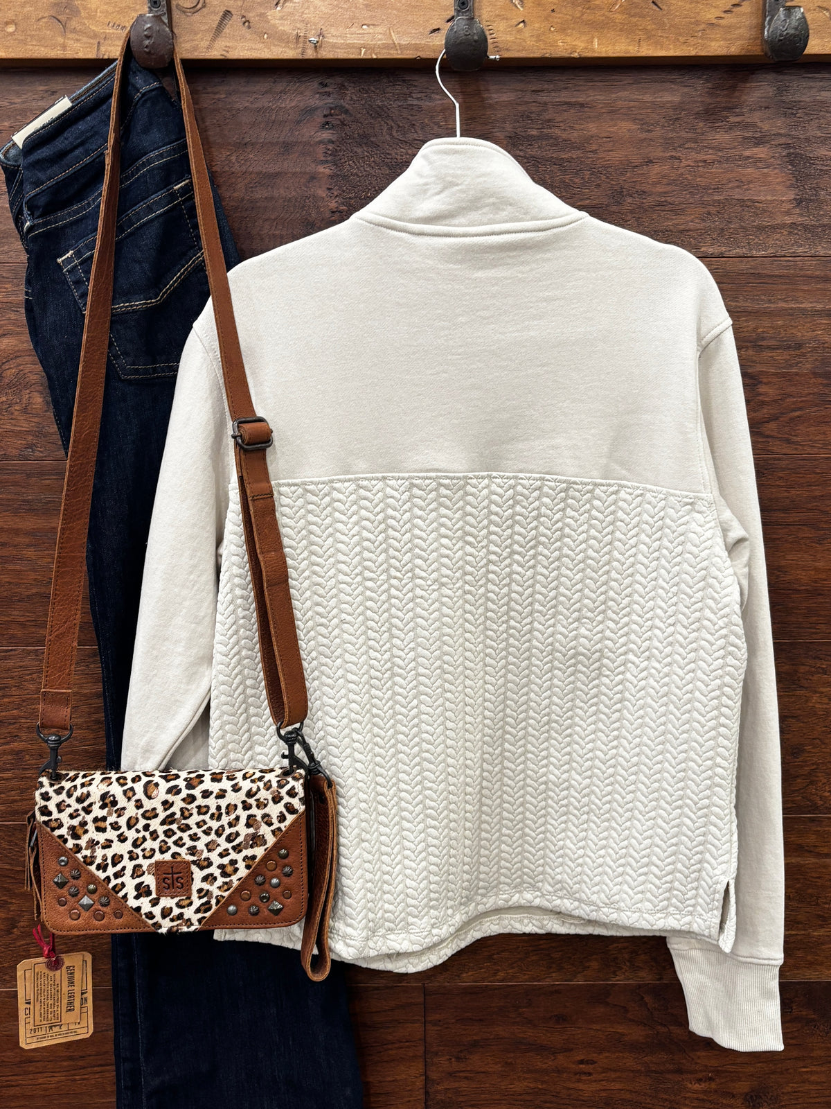 A cream-colored quarter-zip pullover sweater with a textured chevron pattern on the lower half