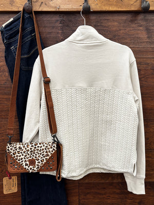 A cream-colored quarter-zip pullover sweater with a textured chevron pattern on the lower half