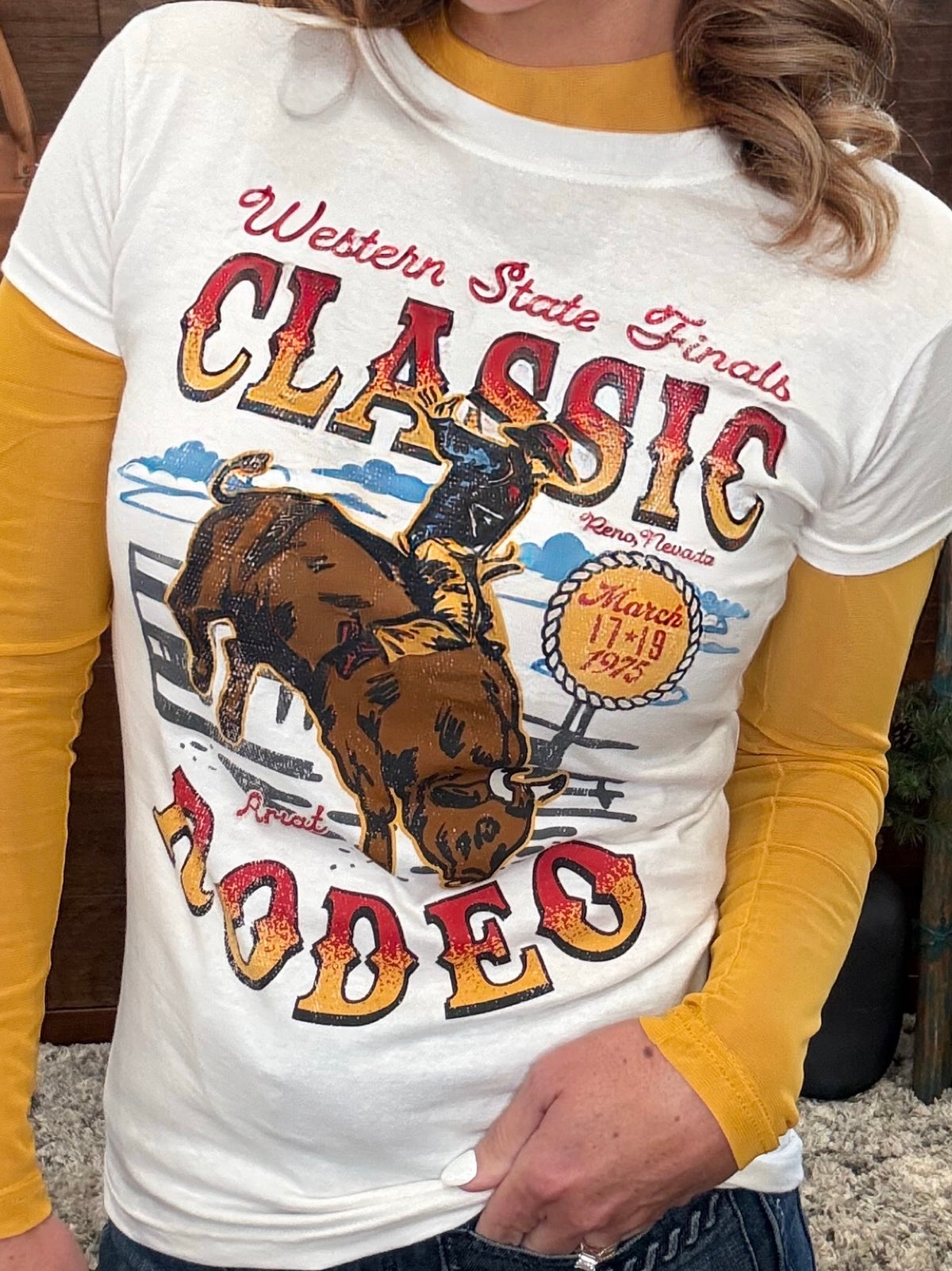 A woman wearing a white graphic t-shirt with a rustic western theme, featuring a brown steer graphic and the words 'Western State Fairs Classic Rodeo', 