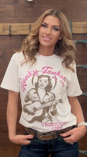Woman wearing a t-shirt with a graphic design of a woman playing guitar and text.