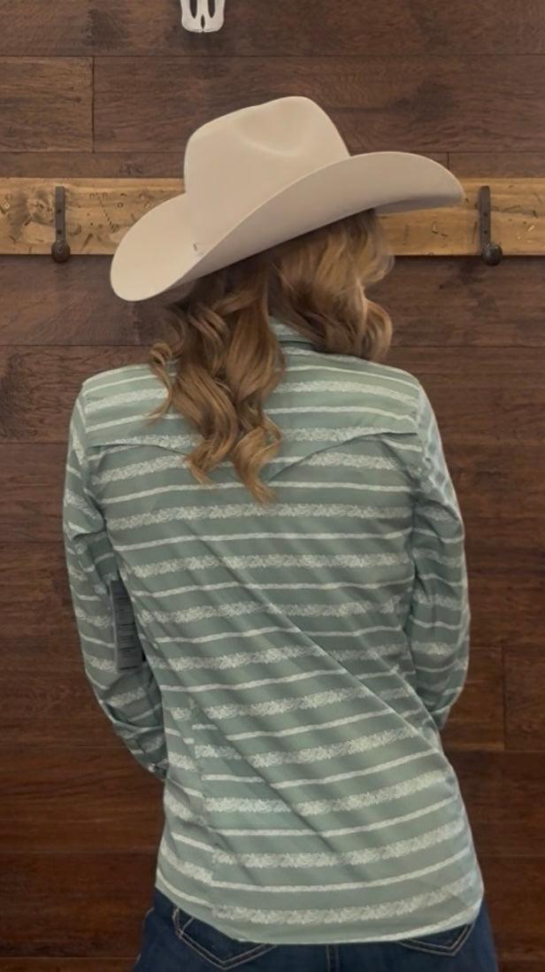 Person wearing a green and white striped shirt and beige cowboy hat against a wooden background