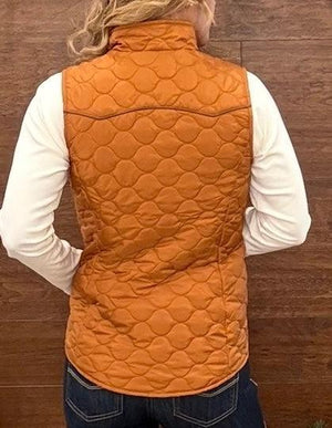 A person shown from the back wearing an orange quilted puffer vest over a white long-sleeve shirt and blue jeans, standing against a dark wood plank wall.