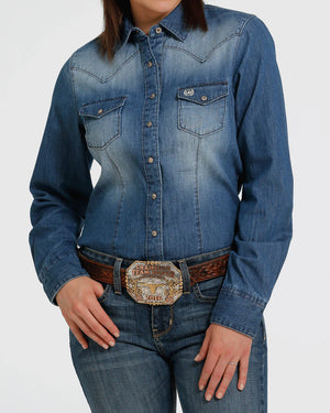 Person wearing a blue denim shirt and jeans with a belt on a white background