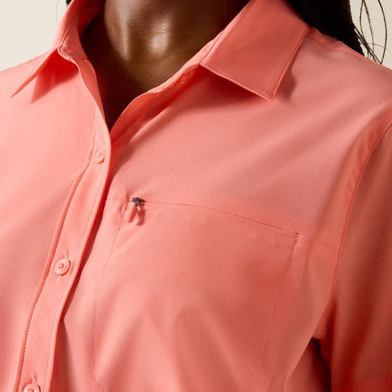 Close-up of a person wearing a light pink shirt with a pocket detail.