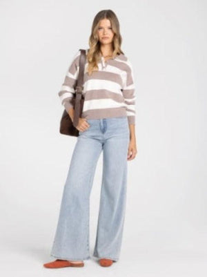 A woman wearing a cropped long-sleeve knit sweater with horizontal taupe and white stripes