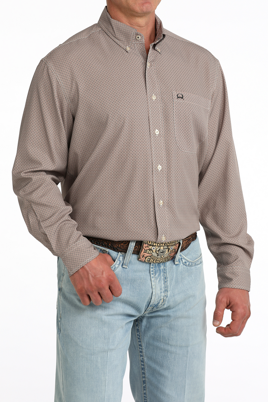 Man wearing a patterned beige shirt and light blue jeans on a white background