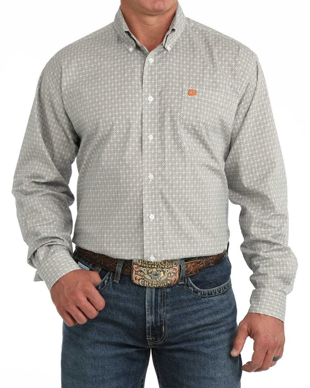 A man wearing a liwhite micro-patterned button-down shirt with a small orange logo on the chest, tucked into blue jeans with a western belt.