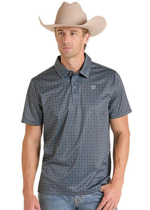A man wearing a short-sleeve polo shirt with a small white geometric pattern on a dark gray background, paired with a beige cowboy hat and blue jeans, against a plain white background.