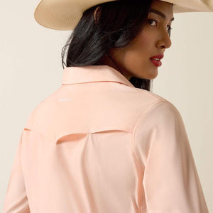 Woman wearing a light peach shirt and blue jeans with a beige hat on a beige background