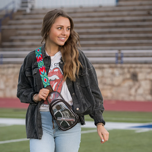 Woman holding a clear bag with a colorful strap on a sports field