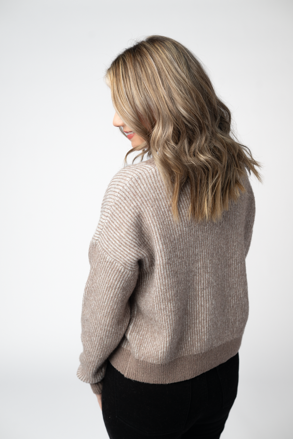 Woman wearing a beige sweater against a white background