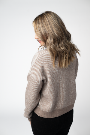 Woman wearing a beige sweater against a white background