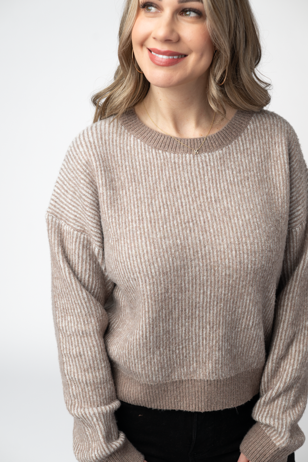 Woman wearing a beige sweater against a white background