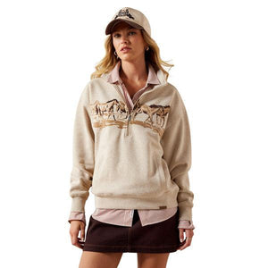 Woman wearing a beige half-zip sweatshirt with graphic designs on a white background