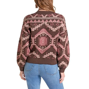 A woman wearing a brown knit sweater with a pink and beige geometric southwestern pattern