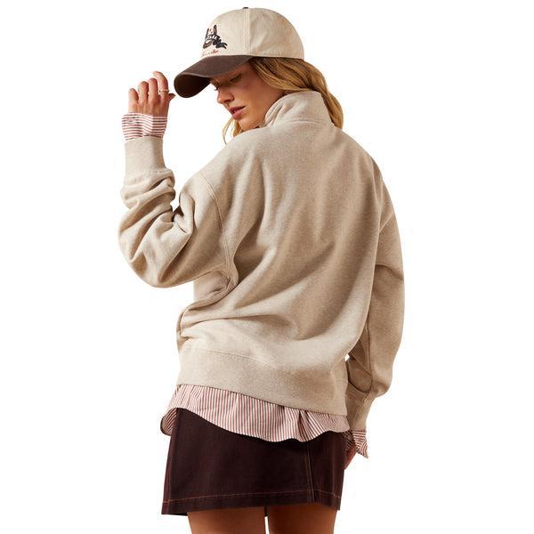 Woman wearing a beige sweatshirt, cap, and skirt on a white background