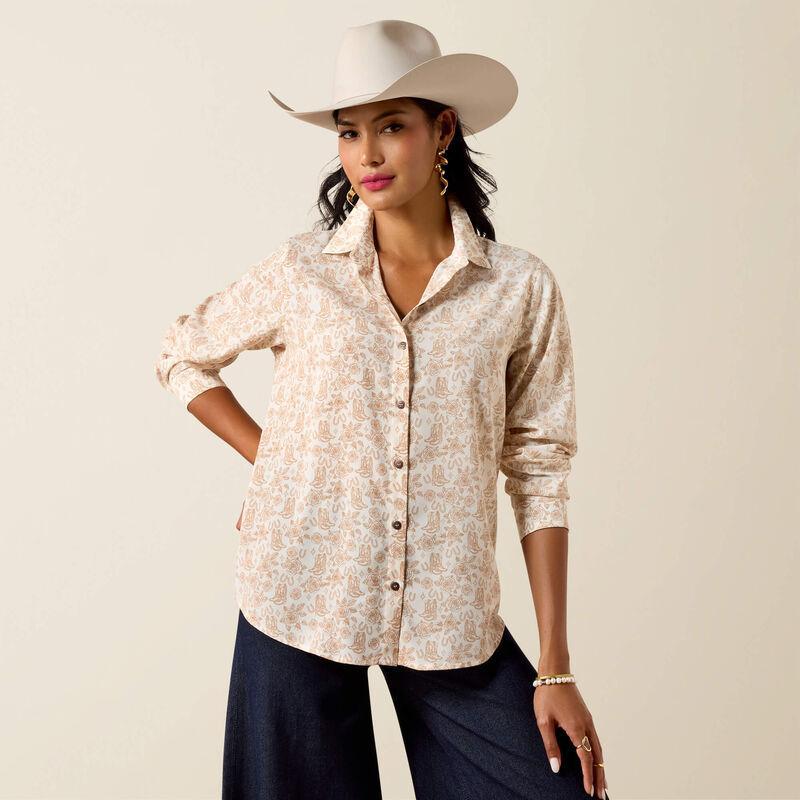 Woman wearing a patterned shirt and wide-brimmed hat against a plain background