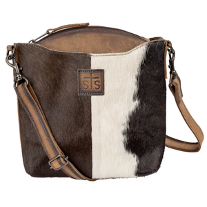 Brown and white cowhide leather bag with brown leather accents on a white background