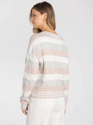 A woman wearing a textured, striped knit sweater in shades of beige, cream, and Grey