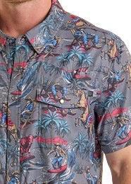 Close-up of a person wearing a patterned shirt with birds and palm trees.