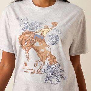 Gray t-shirt with a graphic of a person riding a horse and flowers on a beige background