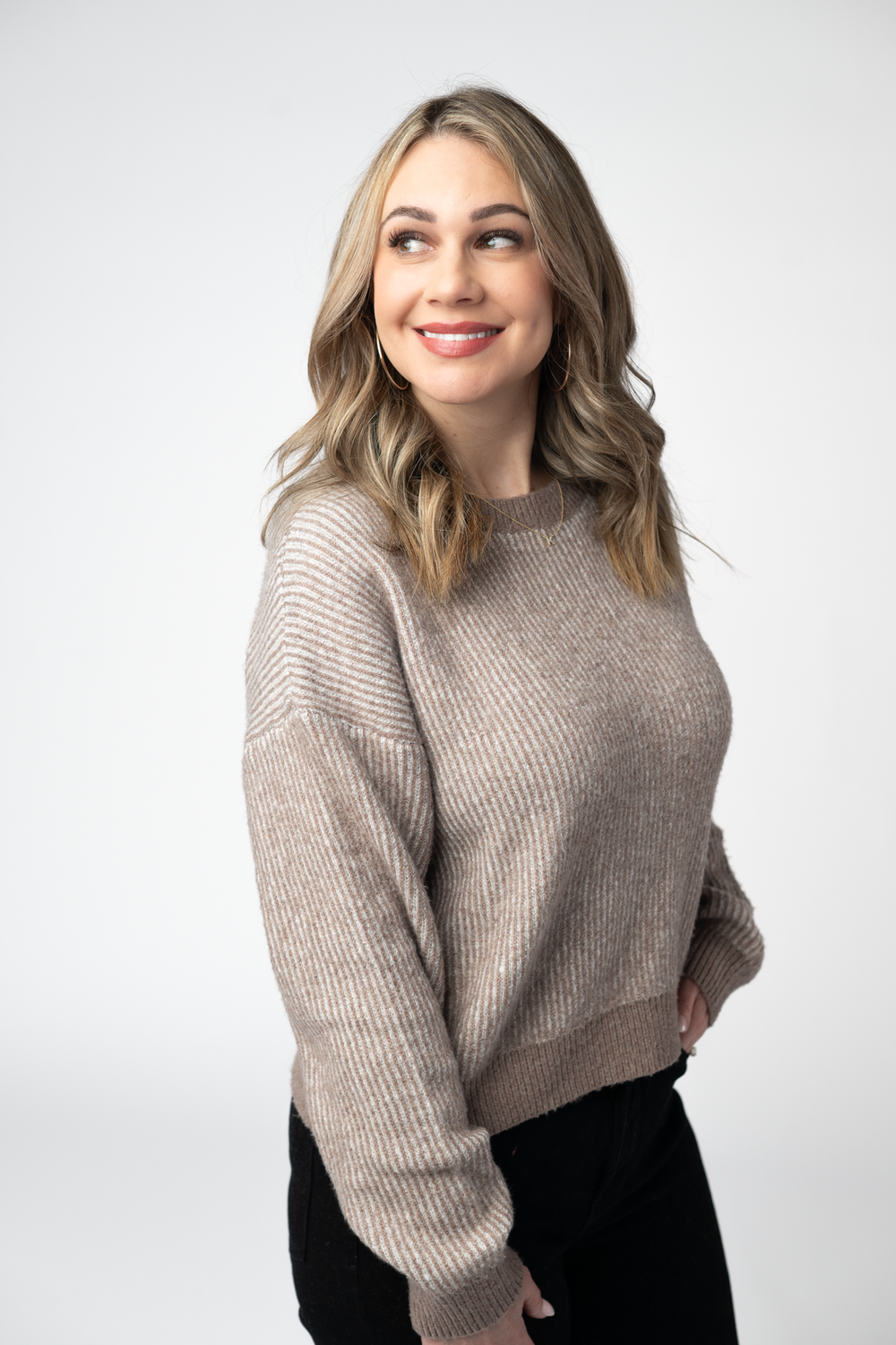 Woman wearing a beige sweater against a white background