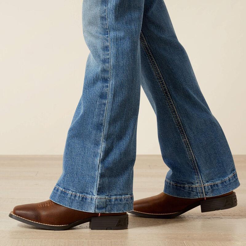 Blue jeans and brown shoes on a light wooden floor.