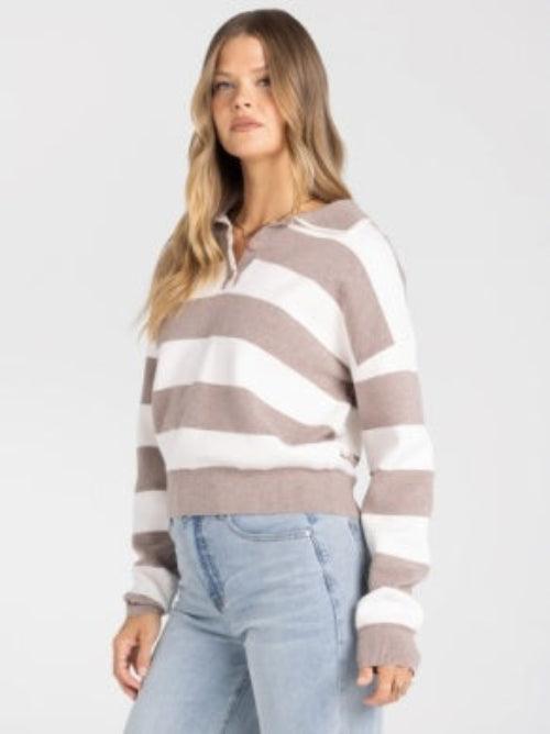 A woman wearing a cropped long-sleeve knit sweater with horizontal taupe and white stripes