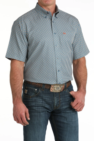 Man wearing a patterned short-sleeve shirt and jeans on a white background