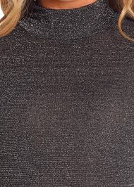 A woman wearing a black long-sleeve mock neck top. 
