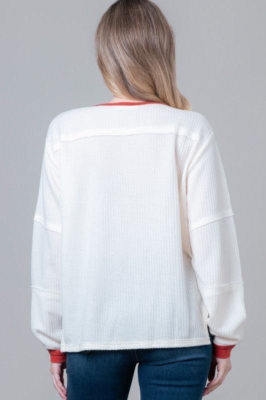 Woman wearing a white sweater with red accents 