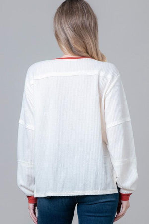 Woman wearing a white sweater with red accents 