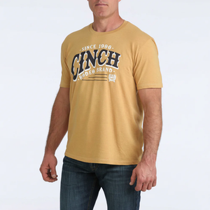 Man wearing a mustard yellow t-shirt with 'Clinch Brand' logo on a white background