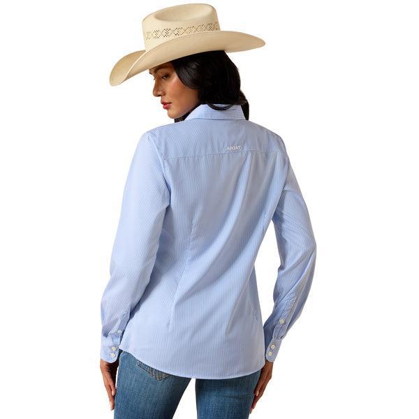 Woman wearing a light blue shirt with a brand logo, blue jeans, and a beige cowboy hat on a white background.