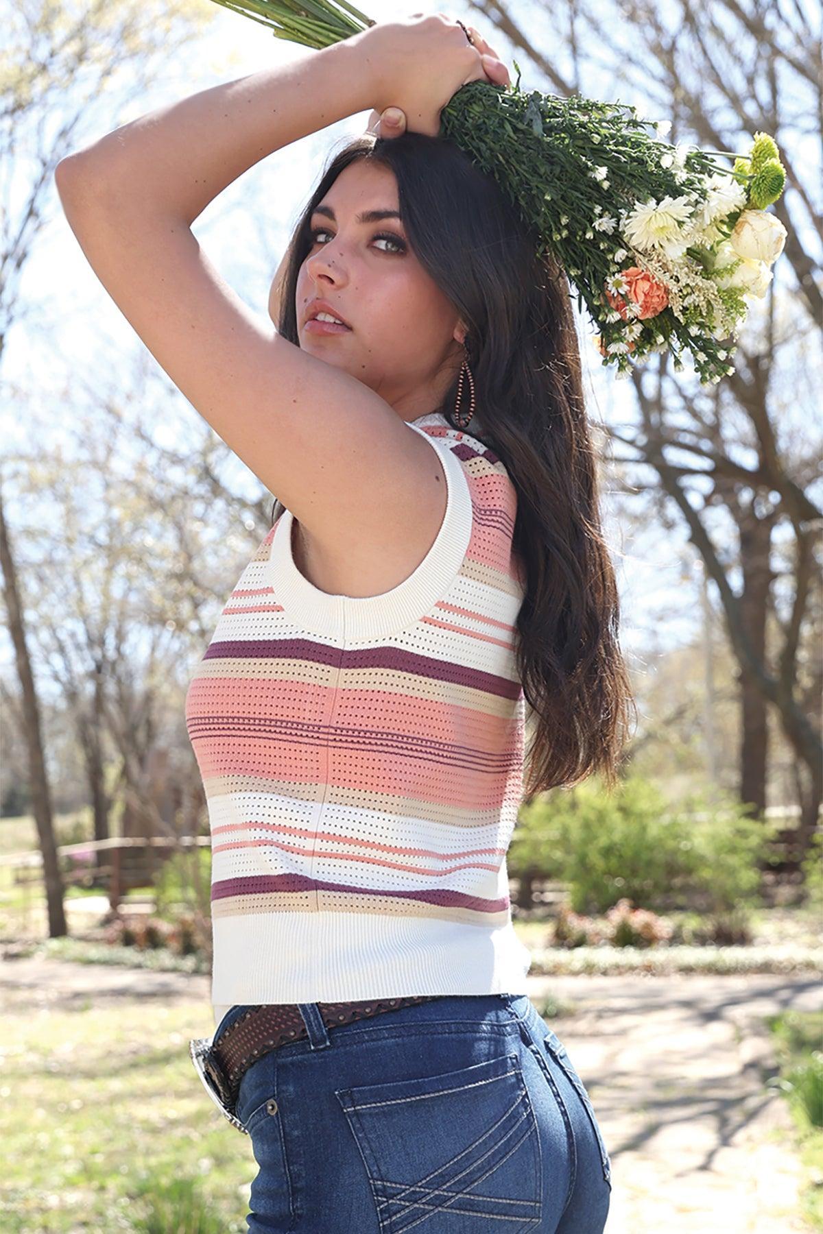 Woman wearing a striped sleeveless top with a belt buckle in an outdoor setting