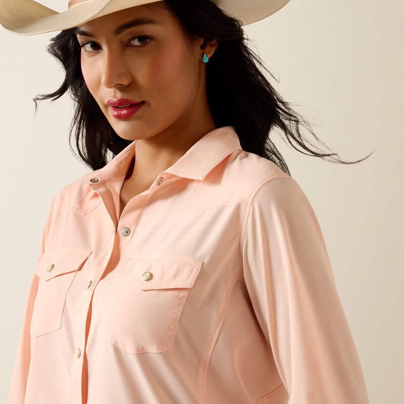 Woman wearing a light peach shirt and blue jeans with a beige hat on a beige background