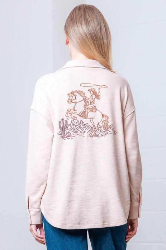 Woman wearing a beige button-up shirt with a horse shoe design on a white background