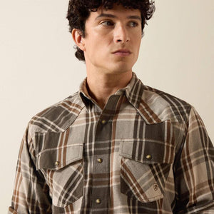 A man wearing a green and beige plaid button-down shirt 