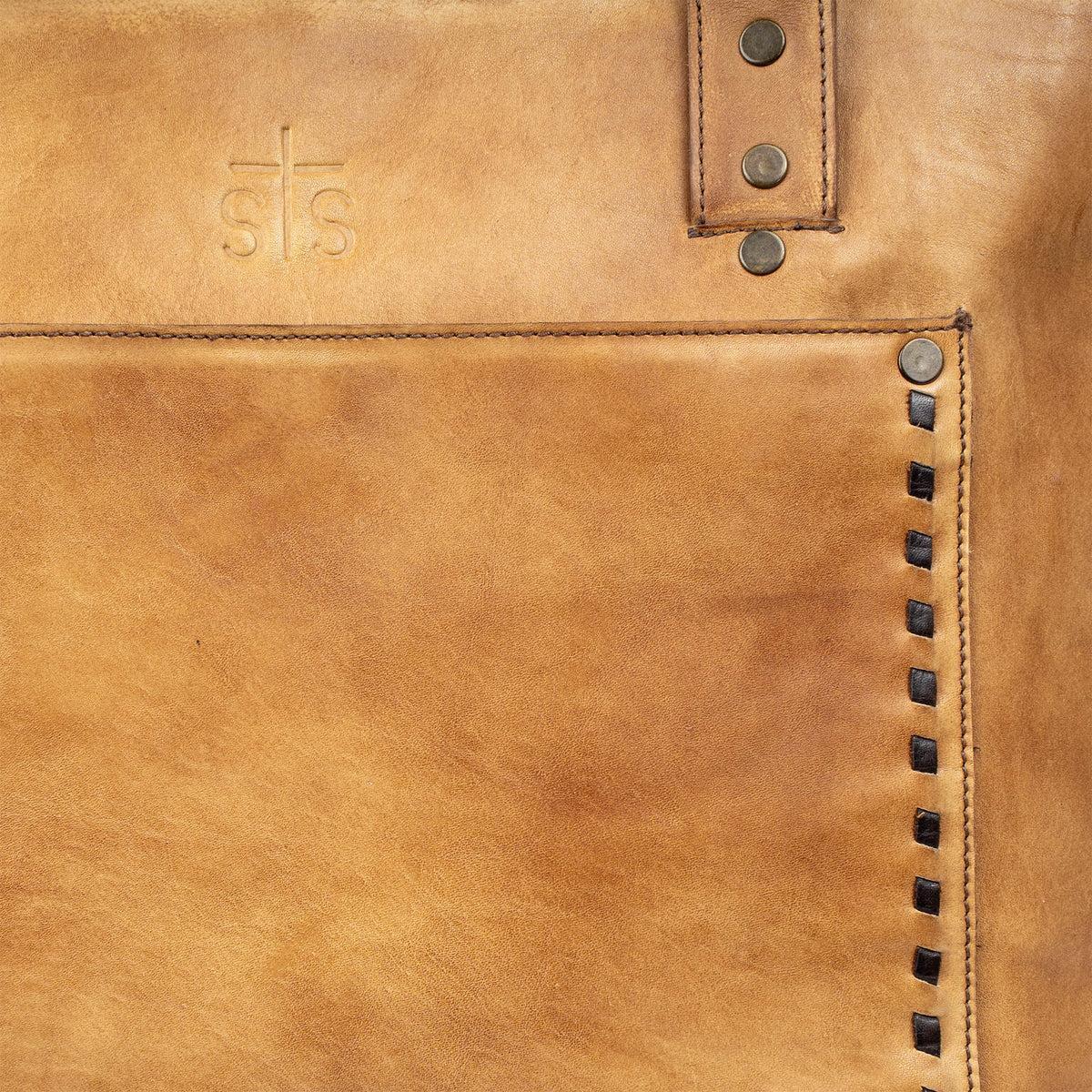 Close-up of a brown leather bag with stitching details and a brand logo.