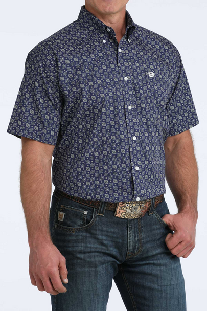Man wearing a patterned blue shirt and jeans on a white background