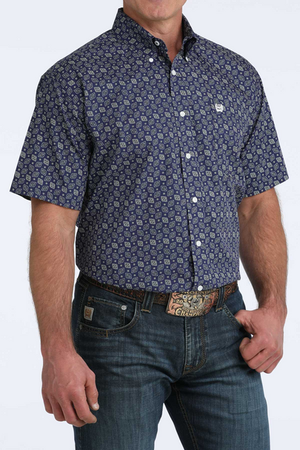 Man wearing a patterned blue shirt and jeans on a white background
